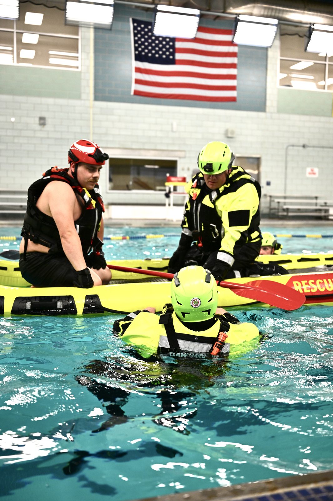First responders training with rescue raft and paddle in pool with American flag