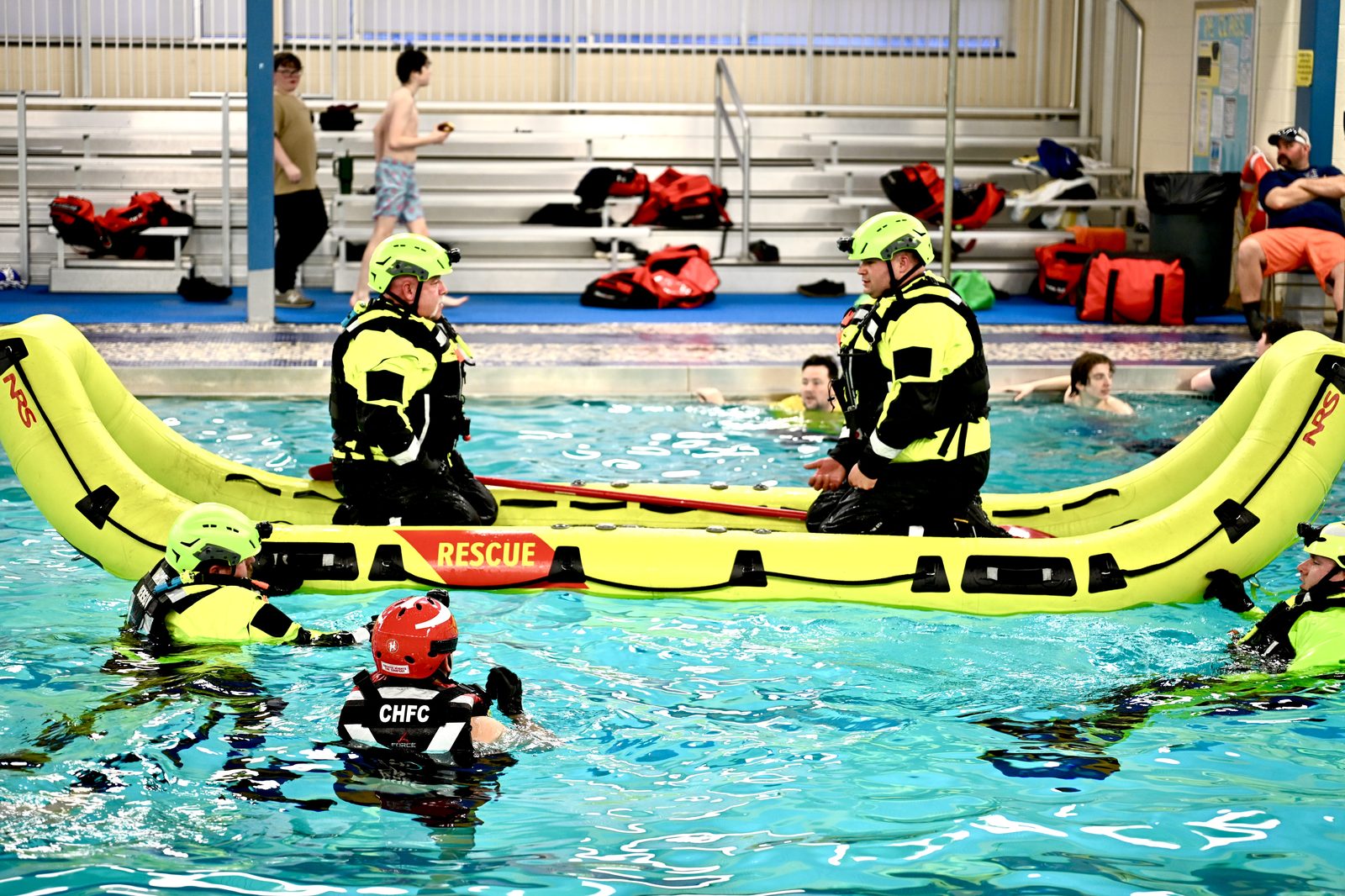 Water rescue team performing extraction drill with inflatable rescue raft in pool