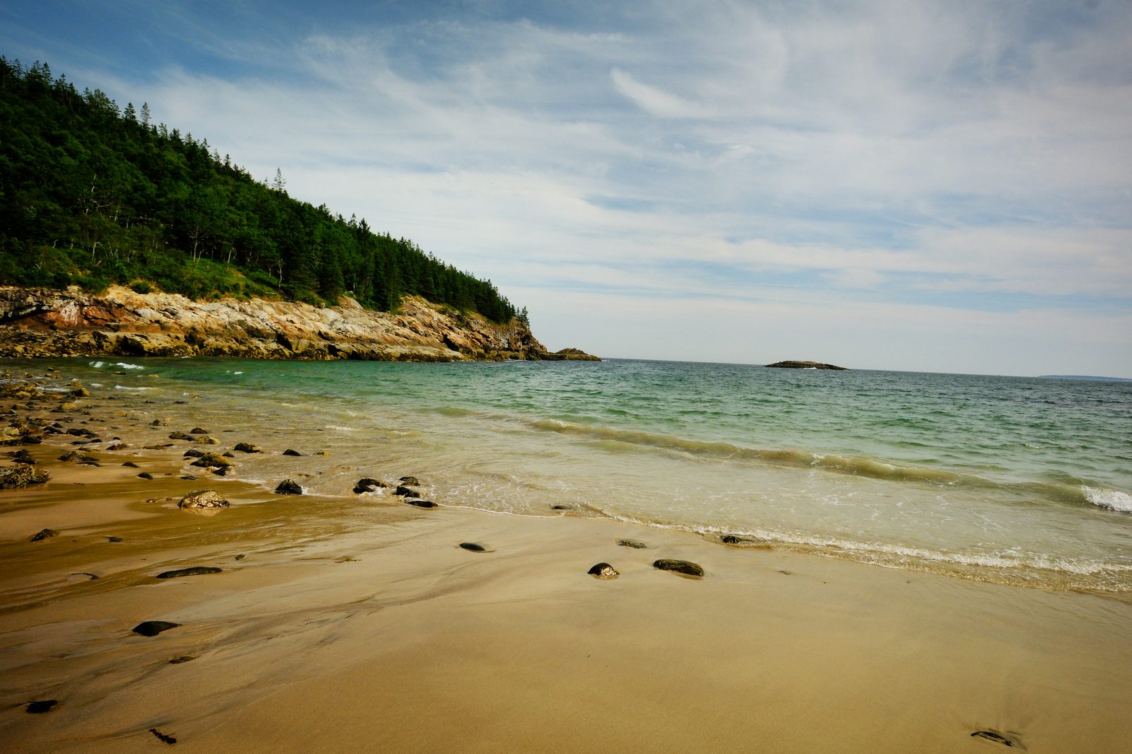 Sandy beach with turquoise water and rocky coastline in Acadia, Maine